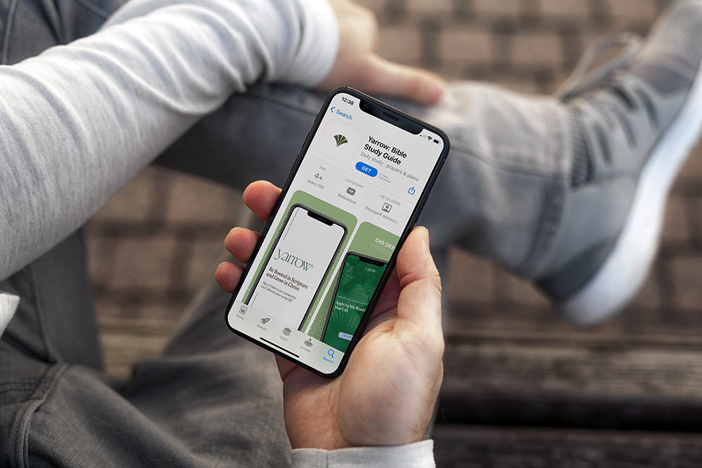 A man holding a smartphone downloading the Yarrow Bible study app
